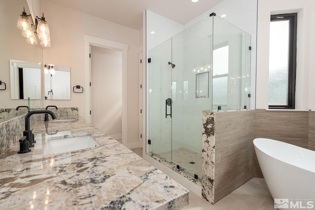 full bath featuring a sink, tile walls, a shower stall, double vanity, and a soaking tub