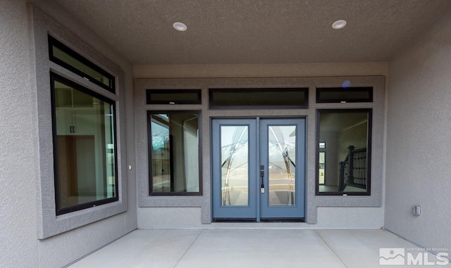 doorway to property featuring french doors and stucco siding