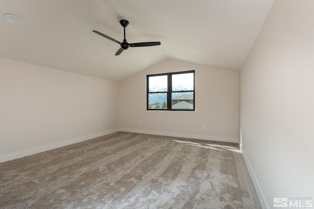 unfurnished room with carpet flooring, ceiling fan, baseboards, and vaulted ceiling