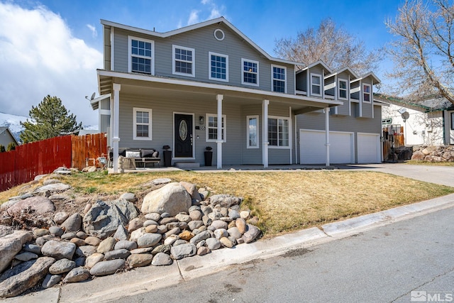 view of front of house with covered porch, an attached garage, concrete driveway, and fence