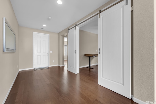 interior space featuring recessed lighting, a barn door, baseboards, and dark wood-style floors