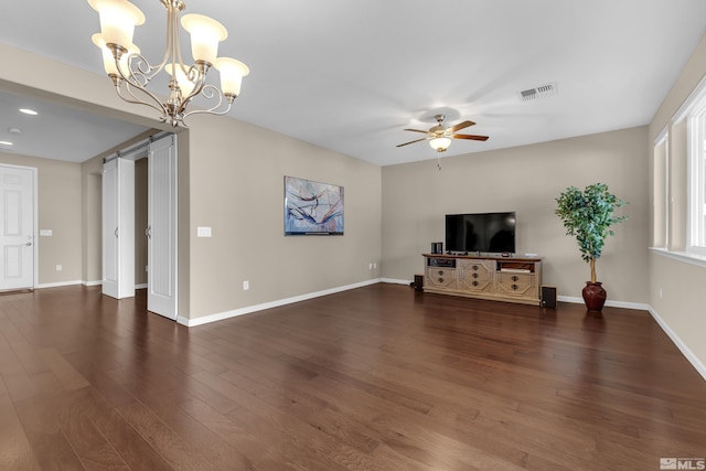 unfurnished living room with wood finished floors, visible vents, baseboards, a barn door, and ceiling fan with notable chandelier