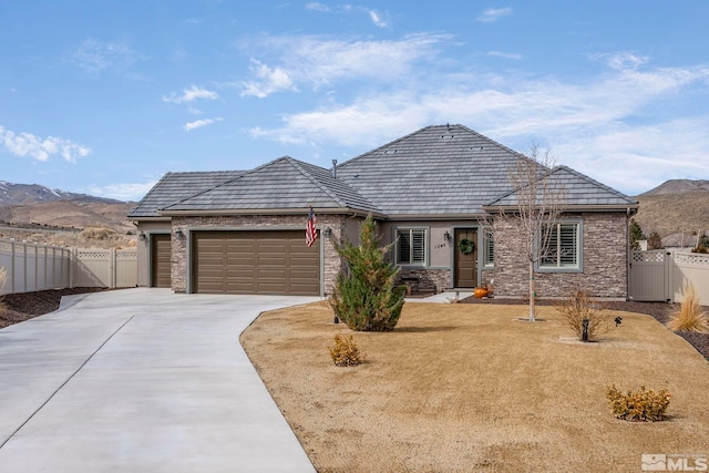 view of front of home with fence, concrete driveway, a garage, a mountain view, and a gate