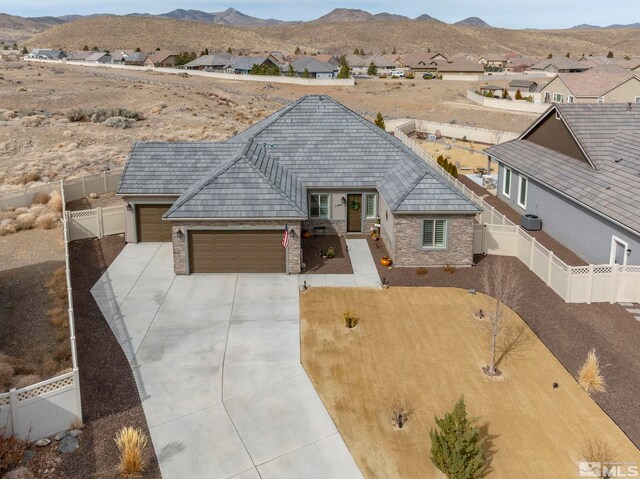 view of front of property with driveway, a garage, a fenced backyard, stone siding, and a mountain view