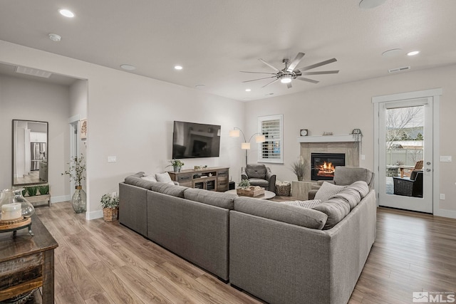 living area featuring visible vents, baseboards, a tiled fireplace, recessed lighting, and light wood-style floors