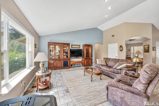 living room with arched walkways, recessed lighting, and high vaulted ceiling