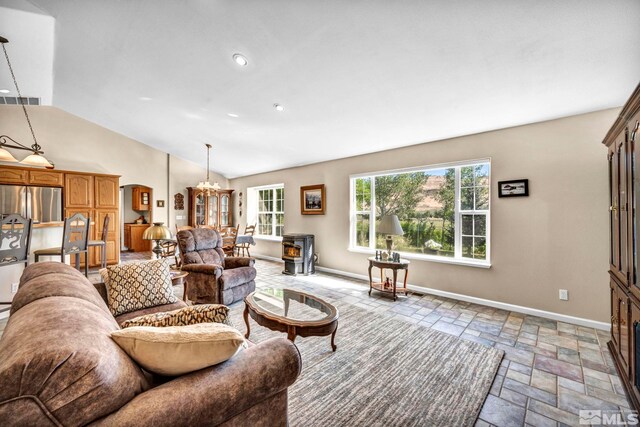 living room with visible vents, lofted ceiling, stone tile flooring, baseboards, and a wood stove