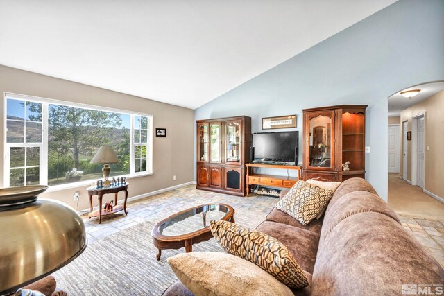 living area with arched walkways, high vaulted ceiling, and baseboards