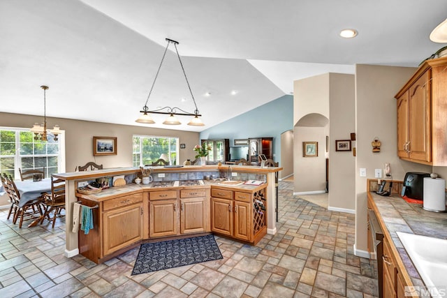 kitchen with pendant lighting, a sink, stone tile flooring, arched walkways, and tile counters