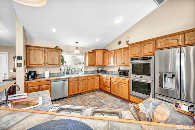 kitchen with a sink, hanging light fixtures, light countertops, vaulted ceiling, and stainless steel appliances