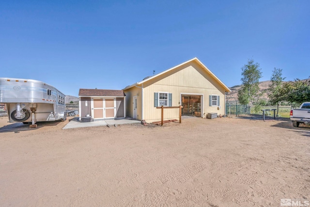 back of property with an outbuilding, a storage unit, and fence