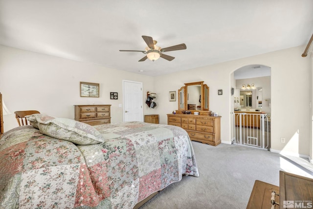 bedroom featuring ceiling fan, light colored carpet, arched walkways, and baseboards