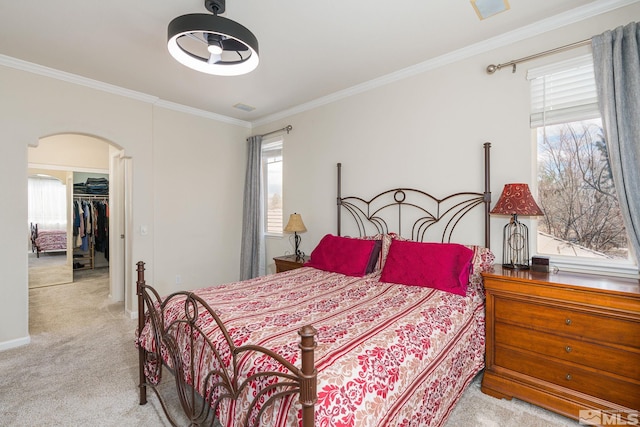 bedroom featuring visible vents, ornamental molding, arched walkways, carpet, and a spacious closet