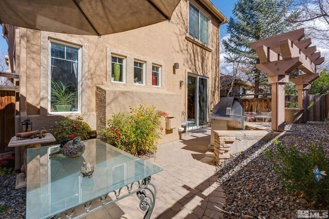 back of property featuring stucco siding, area for grilling, outdoor dining space, a patio, and fence