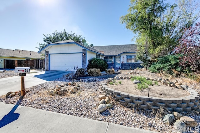 ranch-style house with stone siding, an attached garage, driveway, and fence