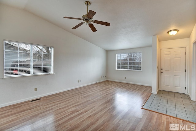 entryway featuring baseboards, visible vents, light wood finished floors, ceiling fan, and vaulted ceiling