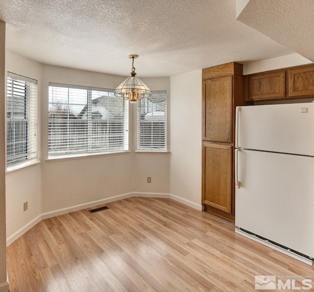 kitchen featuring light wood finished floors, visible vents, brown cabinets, and freestanding refrigerator