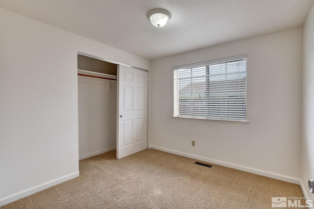 unfurnished bedroom with visible vents, light carpet, a textured ceiling, a closet, and baseboards