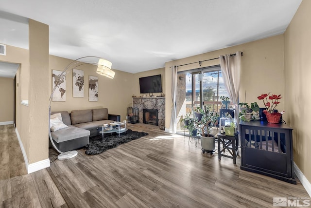 living room featuring visible vents, baseboards, wood finished floors, and a fireplace