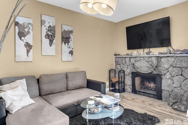 living room with a stone fireplace and wood finished floors