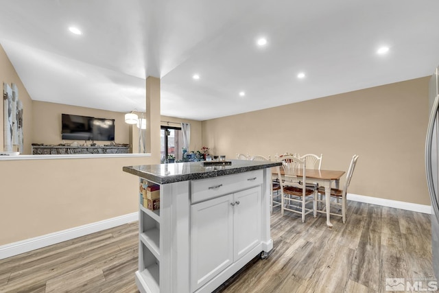 kitchen with open shelves, a kitchen island, light wood-style floors, white cabinets, and baseboards