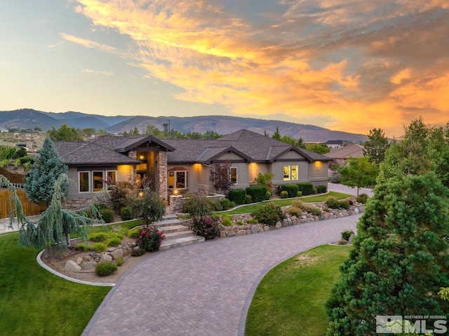 prairie-style house featuring stone siding, stucco siding, a mountain view, and a front yard