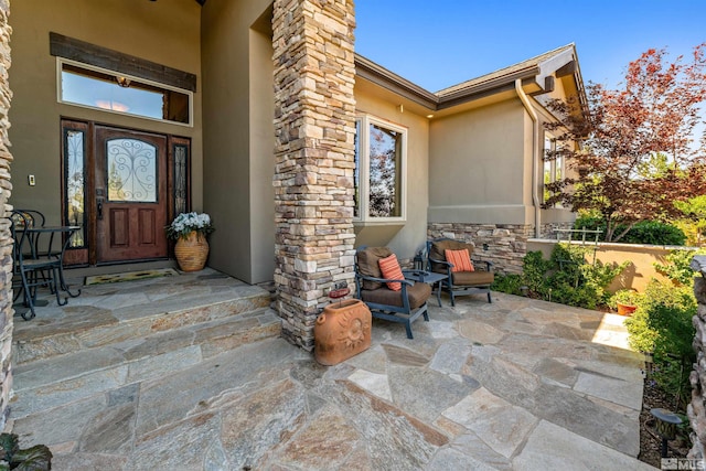 entrance to property featuring a chimney, stone siding, and stucco siding