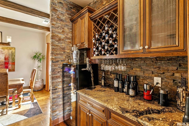 kitchen with visible vents, glass insert cabinets, beamed ceiling, wood finished floors, and brown cabinetry