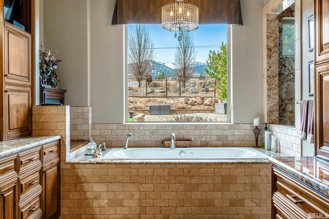 full bath with an inviting chandelier, a mountain view, and a garden tub