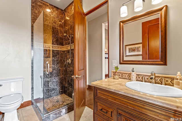 bathroom with vanity, toilet, a shower stall, and tile patterned flooring