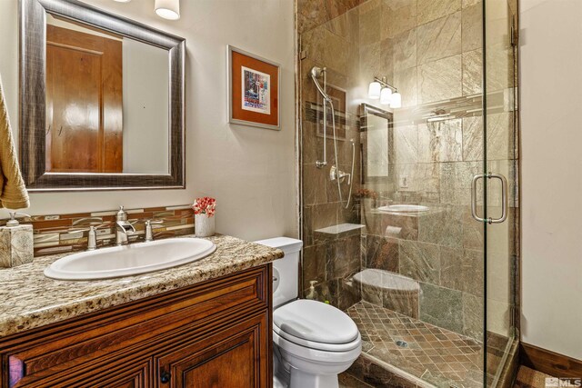 full bathroom featuring vanity, toilet, and a shower stall