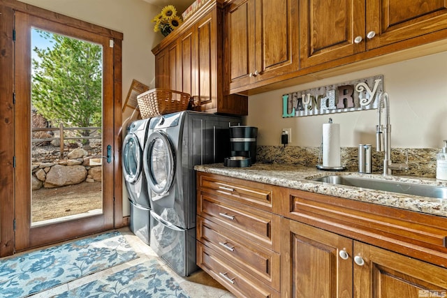 clothes washing area featuring cabinet space, independent washer and dryer, and a sink