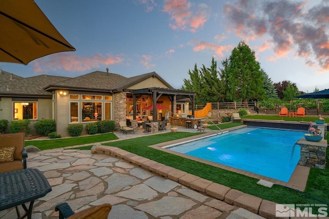 pool at dusk featuring a patio, fence, and a fenced in pool