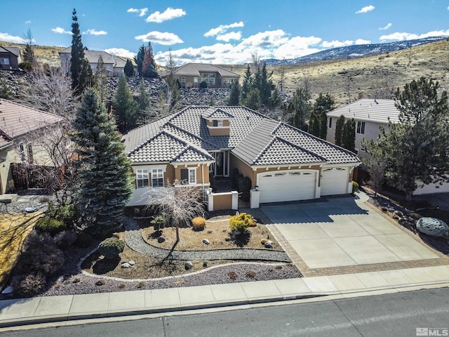 mediterranean / spanish-style house featuring a tile roof, stucco siding, driveway, a garage, and a mountain view