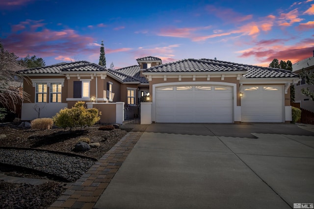 mediterranean / spanish house featuring a tiled roof, stucco siding, an attached garage, and concrete driveway