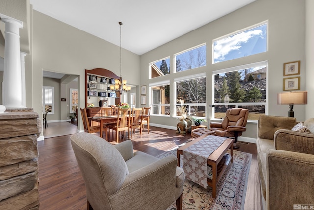 living room featuring an inviting chandelier, a high ceiling, wood finished floors, and baseboards