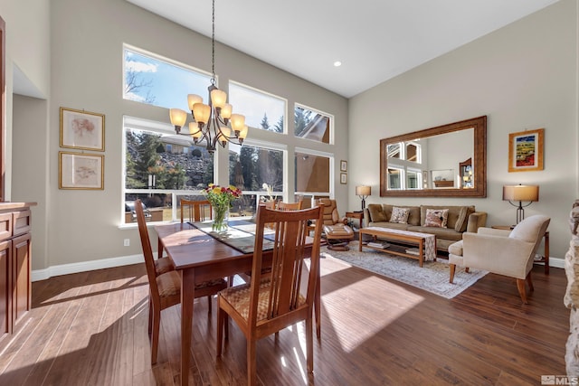 dining space with dark wood finished floors, an inviting chandelier, a high ceiling, and baseboards