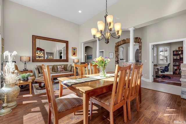 dining area featuring decorative columns, recessed lighting, an inviting chandelier, wood finished floors, and arched walkways