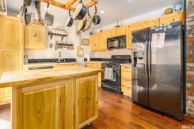 kitchen with black appliances, butcher block countertops, light brown cabinetry, and a sink