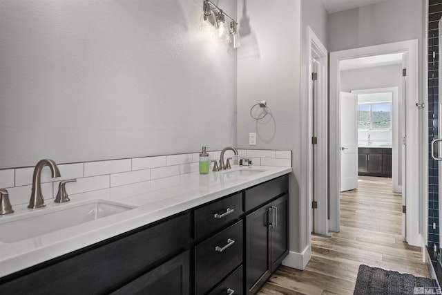 full bathroom with double vanity, wood finished floors, and a sink