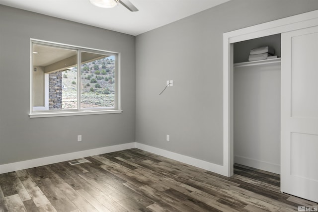 unfurnished bedroom featuring dark wood-style floors, baseboards, and a closet