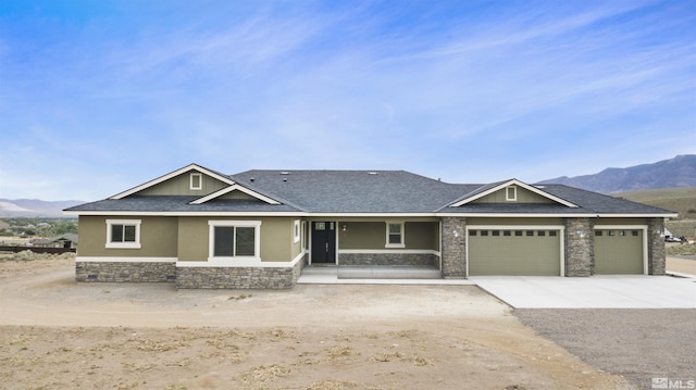 view of front of home with a mountain view, stone siding, a garage, and stucco siding