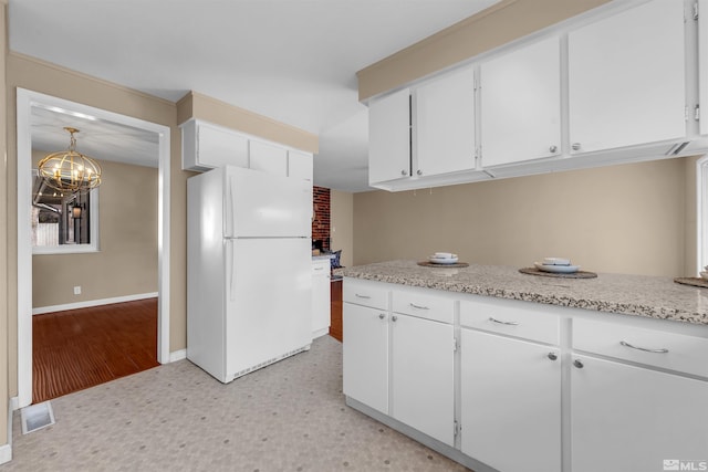 kitchen featuring visible vents, freestanding refrigerator, white cabinets, baseboards, and light floors