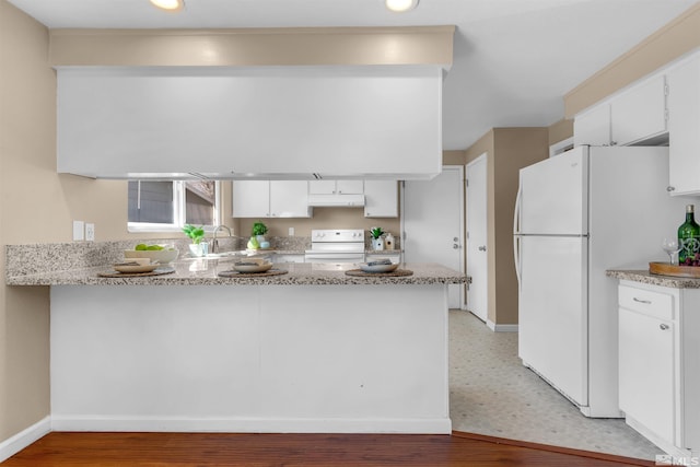 kitchen with under cabinet range hood, a peninsula, freestanding refrigerator, electric stove, and a sink