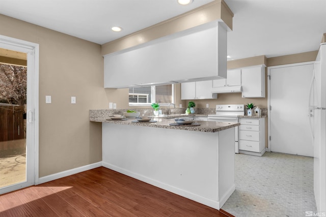 kitchen featuring baseboards, a peninsula, electric range, under cabinet range hood, and white cabinetry