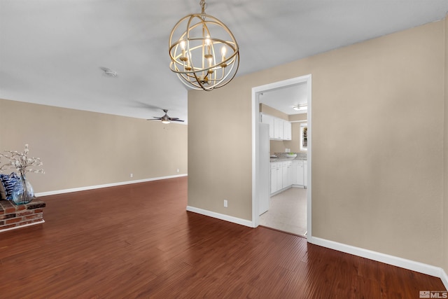 empty room with baseboards, wood finished floors, and ceiling fan with notable chandelier