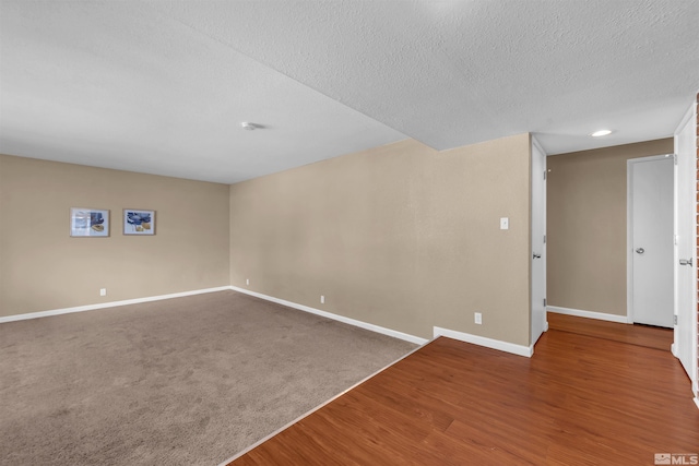 empty room featuring wood finished floors, baseboards, and a textured ceiling