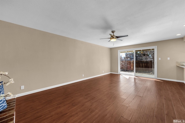 unfurnished living room with ceiling fan, dark wood-type flooring, and baseboards