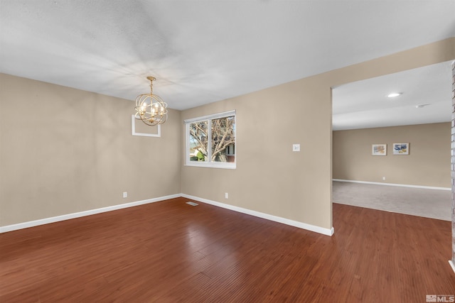 unfurnished room featuring wood finished floors, baseboards, and a chandelier