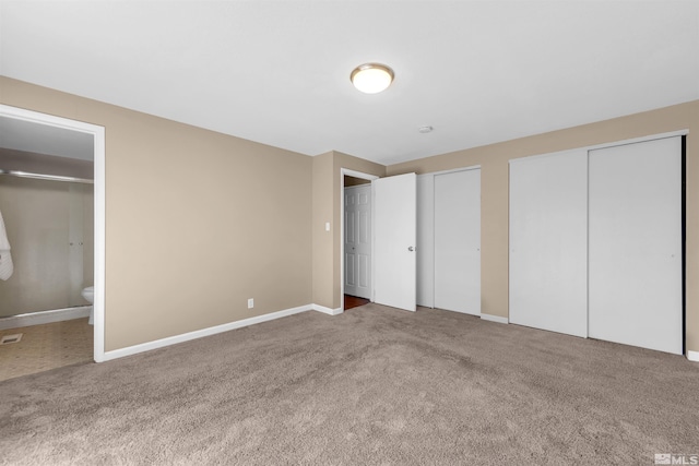 unfurnished bedroom featuring connected bathroom, baseboards, carpet, and multiple closets